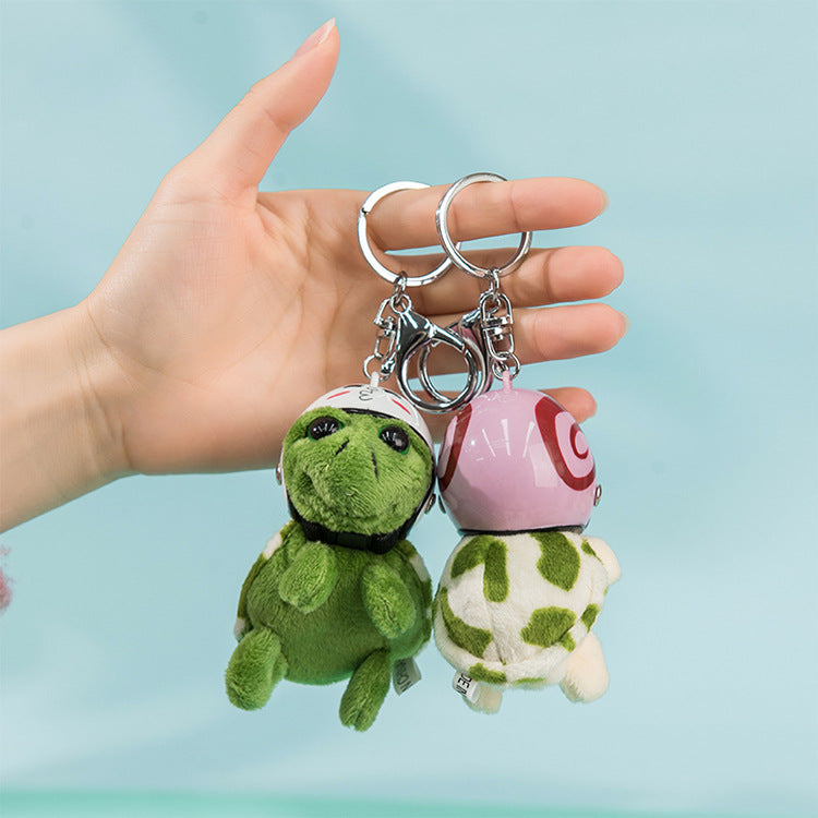Two plush turtle keychains held in a hand against a light blue background